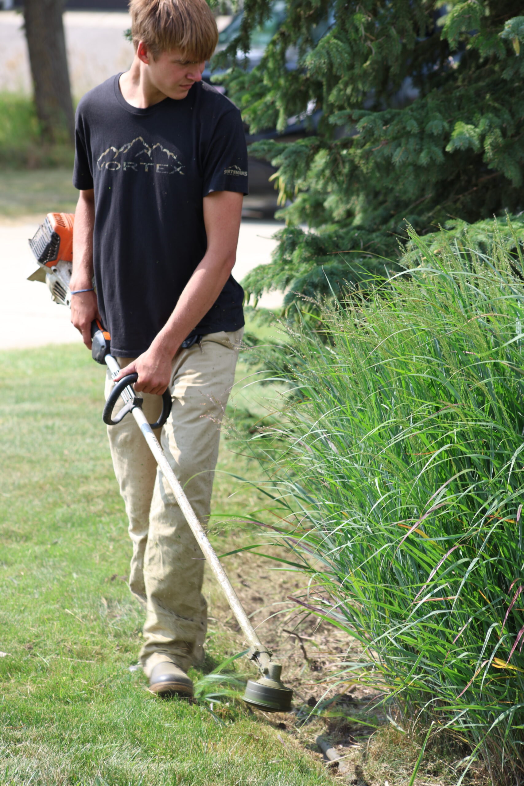 West Property Services crew member using a weed whacker to clean up a client's lawn