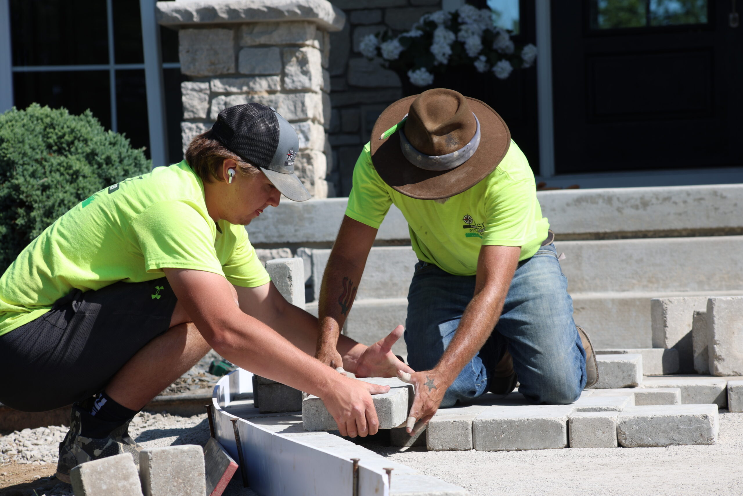 Two men laying stone pavers into a pathway