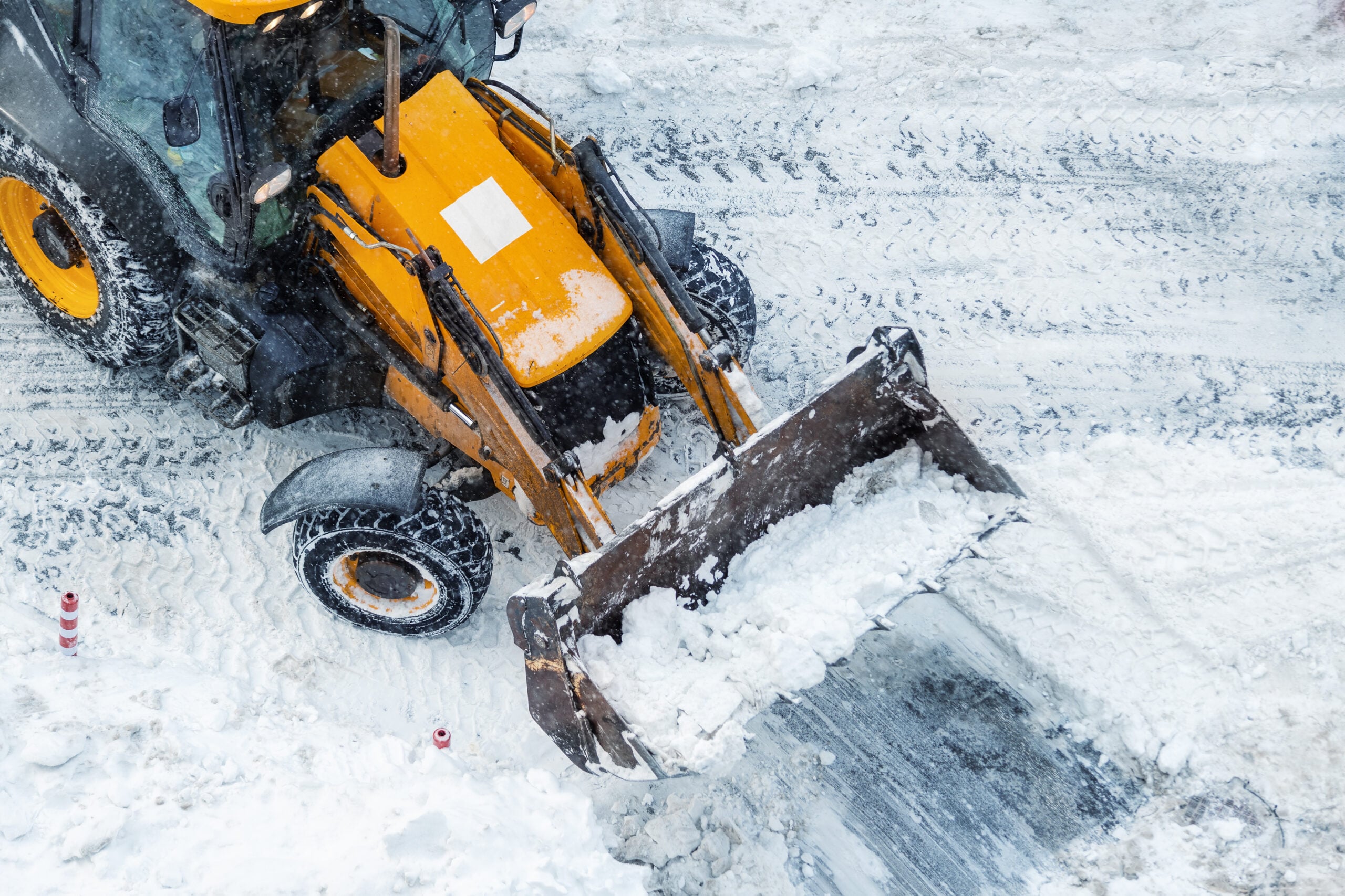 Tractor loader machine removing snow from a large commercial lot