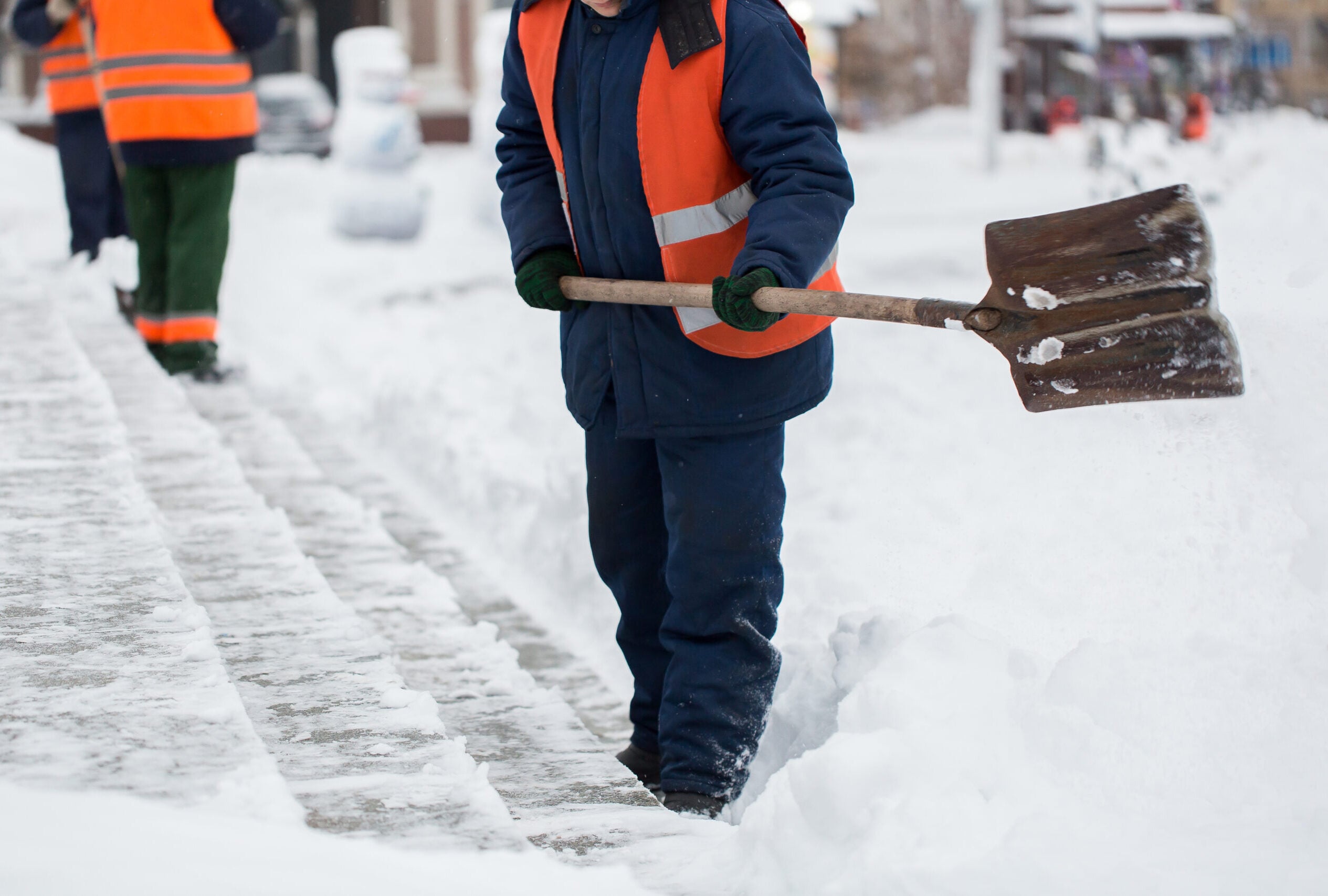 Worker clearing snow from the sidewalk with a shovel